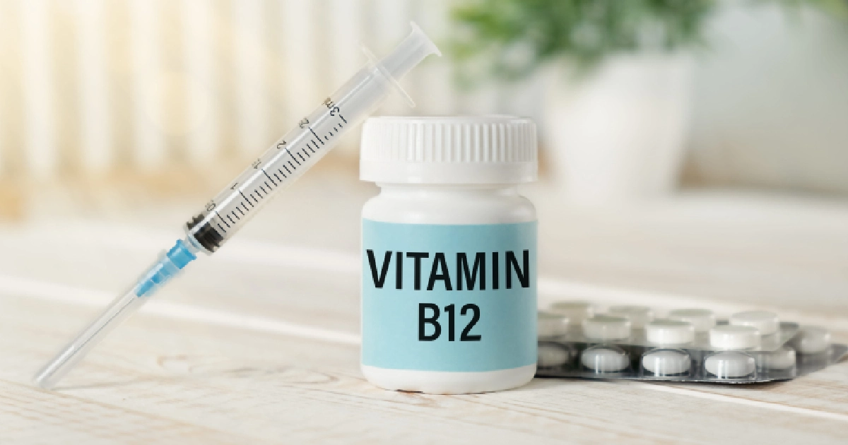 A white Vitamin B12 bottle on a wooden surface with a syringe and pills nearby, showcasing Vitamin B12 Injections in Newport & South Kingstown, RI.